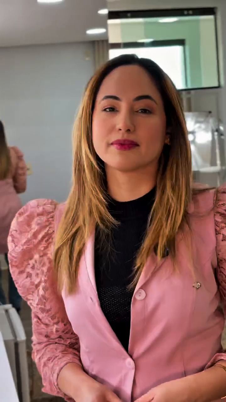 Karla Daniele de blazer rosa no consultório.